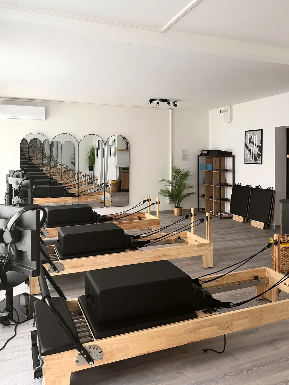 Weiter Blick durch den Trainingsraum auf die Reformer-Reihe und die Spiegelwand.
